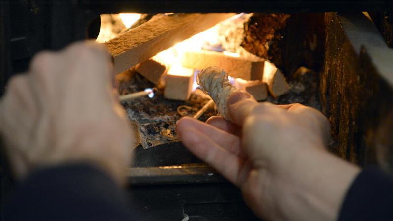 Ein Mann zündet ein Holzfeuer in einem Ofen an.