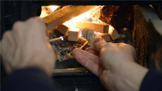 Ein Mann zündet ein Holzfeuer in einem Ofen an.