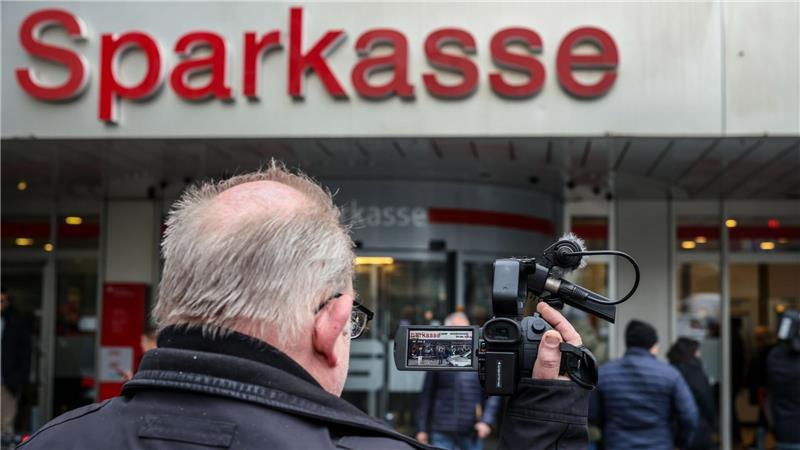 Ein Medienvertreter steht mit einer Kamera vor der Sparkassenfiliale in Buer.