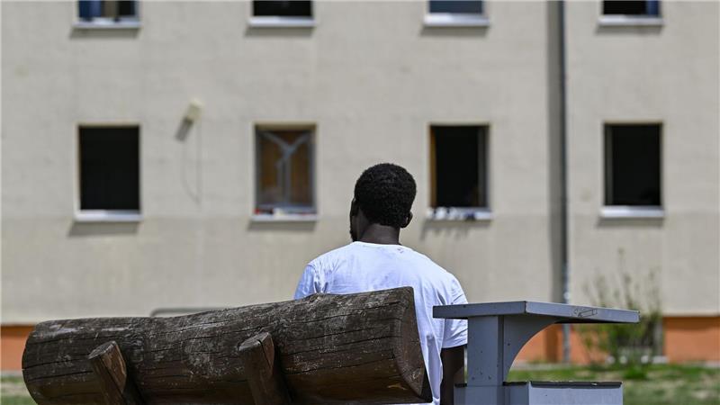 Gerichte heben nur noch relativ wenige Asylbescheide auf Ein Migrant sitzt auf einer Bank auf dem Gelände der Zentralen Erstaufnahmeeinrichtung für Asylbewerber des Landes Brandenburg in Eisenhüttenstadt. (Archivfoto)