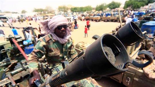 Ein Milizionär sitzt neben militärischer Ausrüstung, die angeblich während eines Gefechts im umkämpften Gebiet in Süd-Darfur erbeutet wurde.