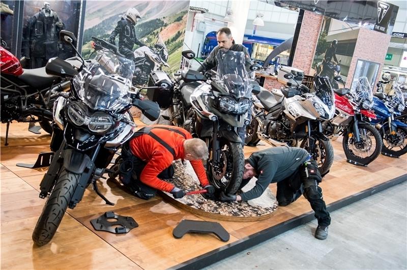 Ein Mitarbeiter befestigt in den Messehallen an einem Messestand ein Motorrad des Herstellers Triumph. Vom 22. bis zum 24. Februar finden die Hamburger Motorradtage statt. Fotos Bockwoldt/dpa