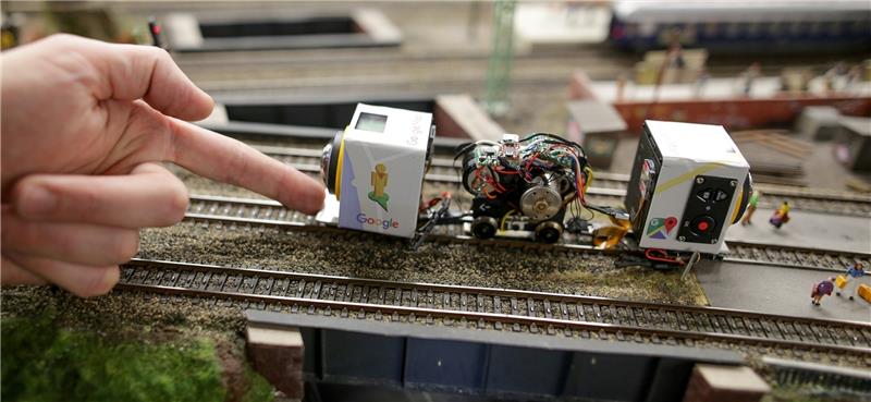 Ein Mitarbeiter des Miniatur Wunderland positioniert einen mit Kameras ausgerüsteten Zug auf Modelleisenbahnschienen, mit dem Aufnahmen der Modellanlage gemacht wurden. Fotos Heimken/dpa
