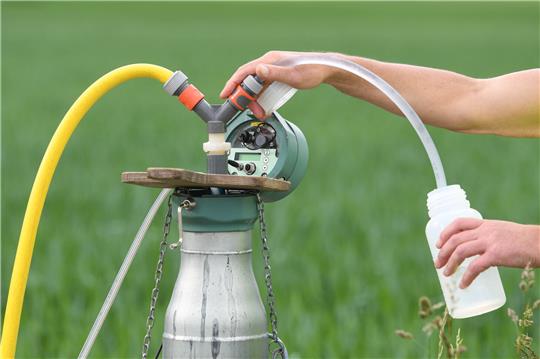 Ein Mitarbeiter des Wasserwirtschaftsamts München entnimmt an einer Grundwassermessstelle eine Wasserprobe. Foto: Tobias Hase/dpa