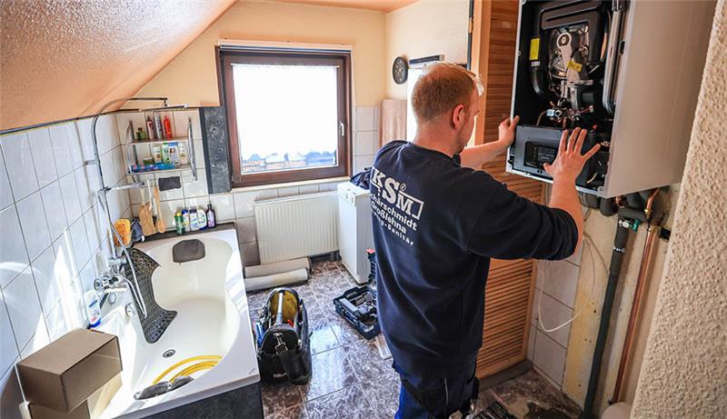 Ein Mitarbeiter einer Sanitär- und Heizungsbaufirma installiert eine moderne Gasbrennwerttherme in einem Einfamilienhaus. Foto: Jan Woitas/dpa