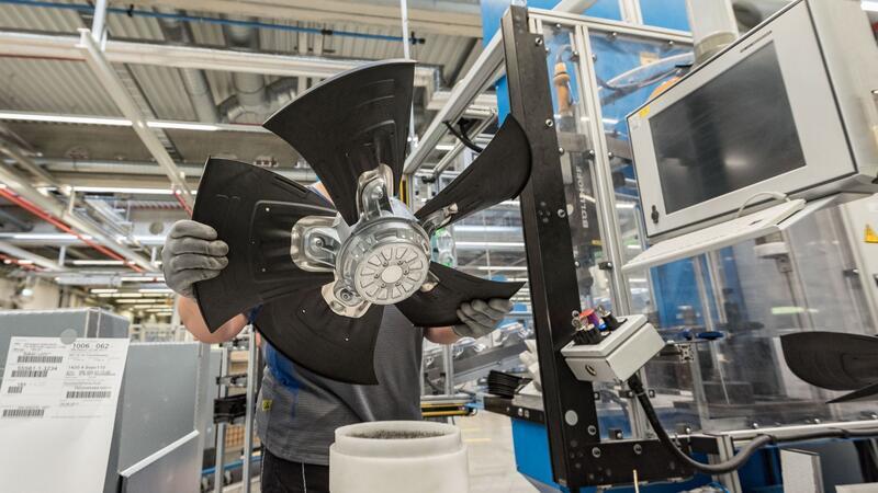 Ein Mitarbeiter eines Herstellers von Ventilatoren und Elektromotoren montiert einen Lüfter.