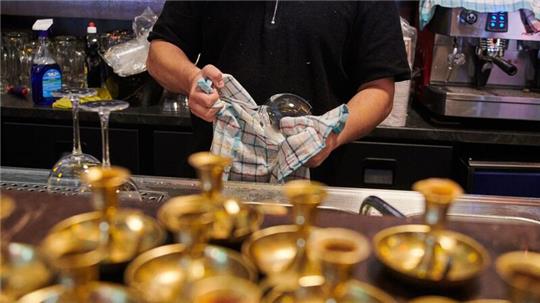 Ein Mitarbeiter eines mexikanischen Restaurants in Prenzlauer Berg poliert die Weingläser.