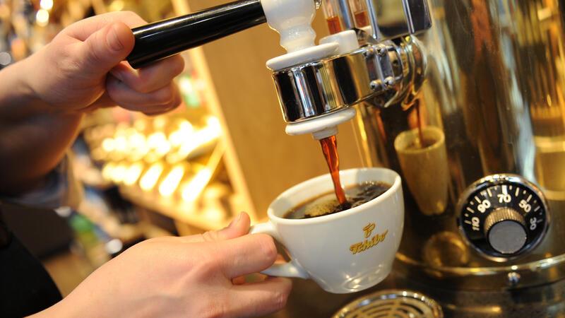 Vom Kaffeeröster zum Gebrauchswarenhändler – Tchibo wird 75 Ein Mitarbeiter füllt in einer Tchibo-Filiale eine Kaffeetasse.