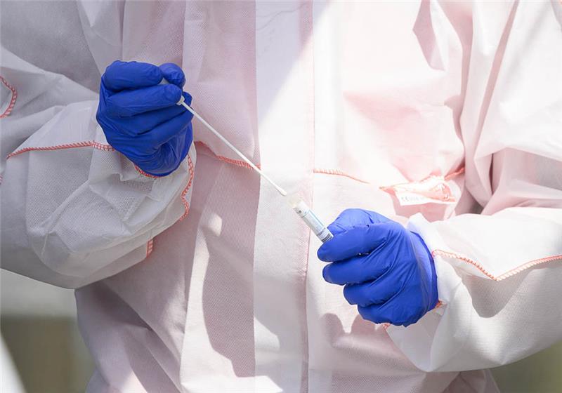 Ein Mitarbeiter hält in einem Corona-Abstrichzentrum einen Test auf das Coronavirus in den Händen (Symbolbild). Foto: Sebastian Gollnow/dpa
