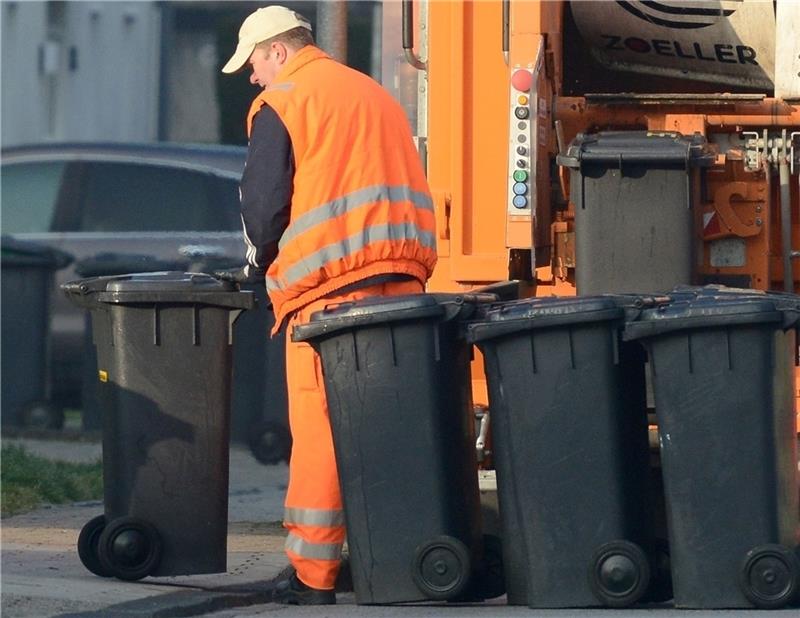 Ein Mitarbeiter holt Mülltonnen an einer Sammelstation ab. (Symbolbild) Foto: Caroline Seidel/dpa