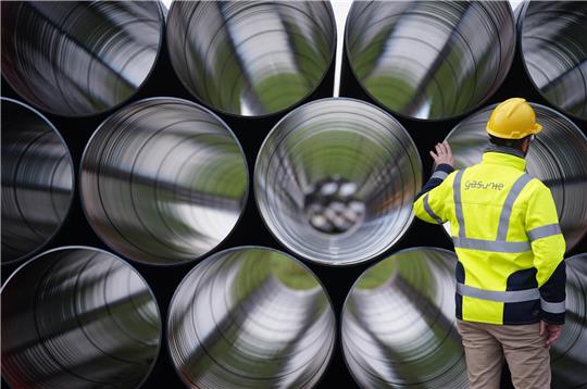 Ein Mitarbeiter steht vor ETL 180 Gasrohren auf dem Rohrlagerplatz von Gasunie Deutschland in Brunsbüttel. Foto: Marcus Brandt/dpa
