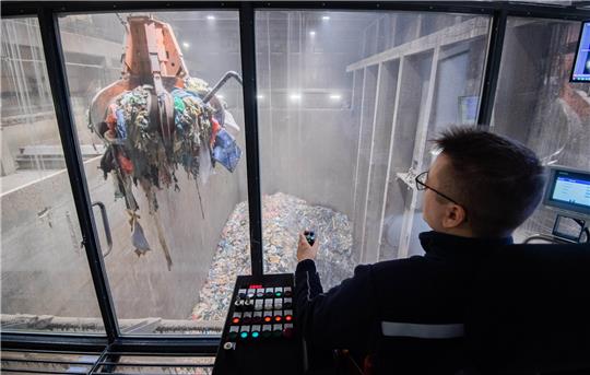 Ein Mitarbeiter transportiert Müll mit einem Kran zum Verbrennen in einer Müllverbrennungsanlage. Foto: Julian Stratenschulte/dpa