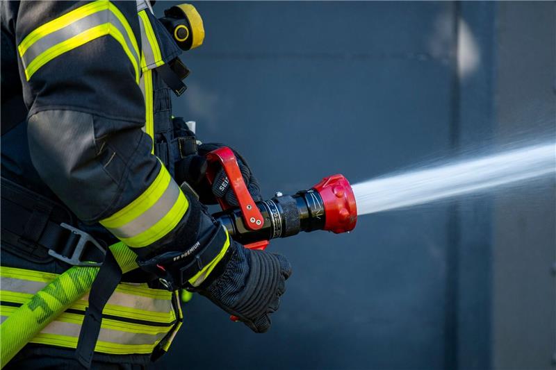 270.000 Euro Schaden bei Treckerbrand in Assel Ein Mitglied der Feuerwehr spritzt aus einem Schlauch mit Wasser.