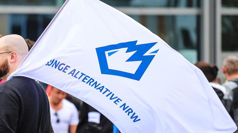 Ein Mitglied der „Jungen Alternative“ (JA) trägt auf einer Wahlkampfveranstaltung in Dortmund eine Fahne mit dem Logo der Organisation.