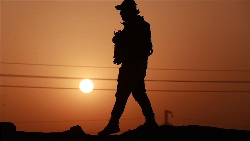 Ein Mitglied der Popular Mobilization Forces läuft an einer Betonmauer entlang.