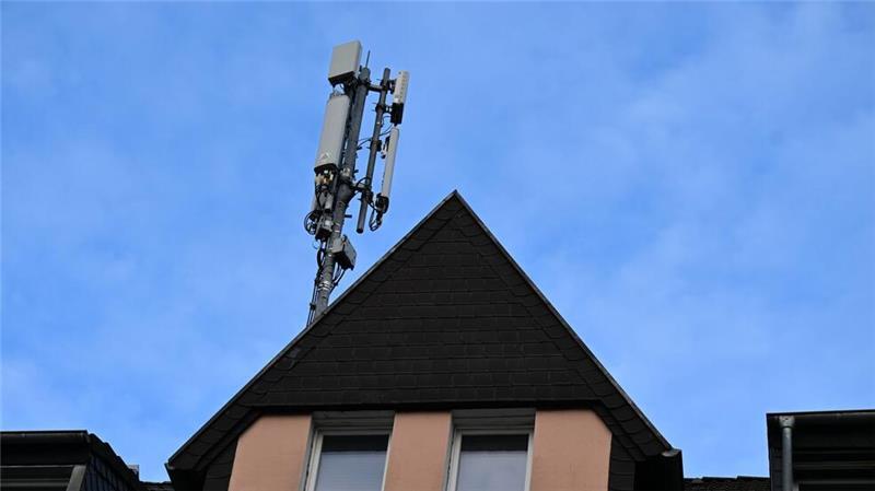 Ein Mobilfunk-Mast mit Antennen im Funkstandard 5G (quadratisch) und 4G (länglich) ist auf dem Dach eines Wohnhauses montiert.