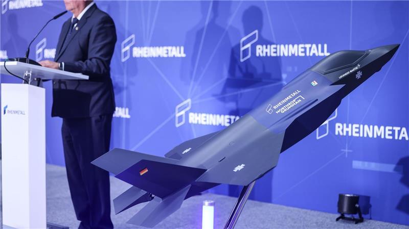 Rheinmetall startet als Zulieferer für Tarnkappenbomber Ein Modell des F-35 auf der Bühne, auf der Konzernchef Papperger zu Mitarbeitern spricht.