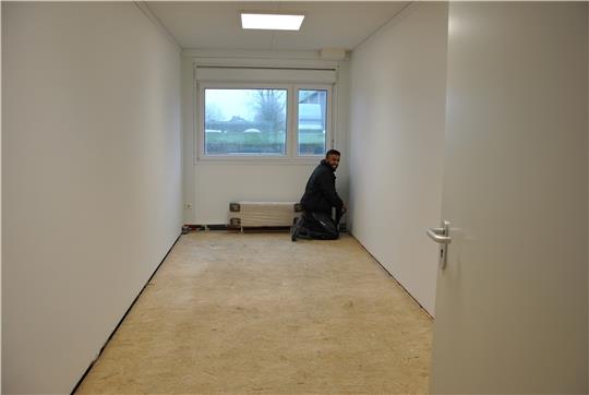 Ein Modul-Kindergarten wird neben der Sporthalle Hermannstraße errichtet: Auch in den Ferien wird gearbeitet, hier montiert Firaz Aslam von der Heizungsbaufirma Tobias Terne einen Heizkörper. Foto: Lohmann