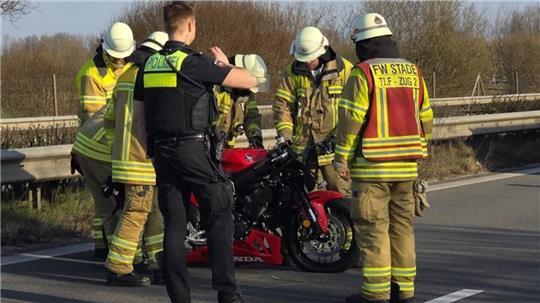 Einsatzkräfte von Feuerwehr und Polizei richten das verunfallte Motorrad auf.