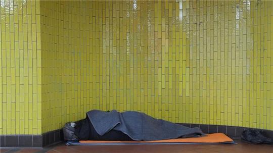 Ein Obdachloser liegt in seinem Schlafsack in einer U-Bahnstation in der Innenstadt.