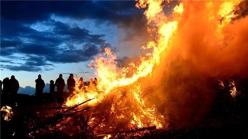 Ein Osterfeuer lodert in der Dämmerung: Der traditionelle Brauch steht zwischen geselligem Frühlingsevent und der Kritik von Natur- und Tierschützern. (Symbolbild)