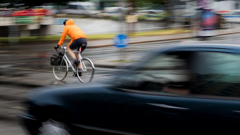 Ein Pkw fährt hinter einem Fahrradfahrer an einer Kreuzung einer Hauptverkehrsstraße in Berlin. Inwieweit Maßnahmen zur Verbesserung der Verkehrssicherheit befürwortet werden, hängt auch stark vom Alter ab.
