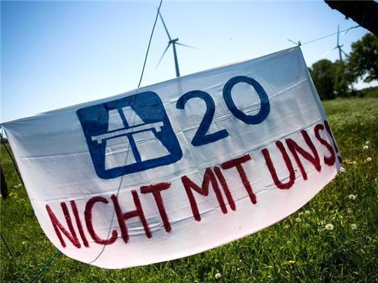 Ein Plakat mit der Aufschrift «A20 Nicht mit uns!» hängt vor dem Protestcamp. Foto: Sina Schuldt/dpa