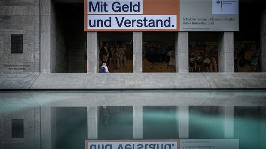Ein Plakat mit der Aufschrift „Mit Geld und Verstand. Schulden bremsen, Chancen schaffen. Unser Bundeshaushalt“ hängt über dem Eingang zum Bundesministerium der Finanzen in Berlin.