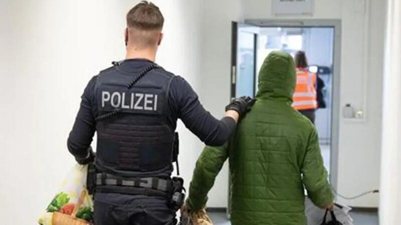 Ein Polizeibeamter bringt einen Mann zu einem Abschiebeflug am Flughafen.