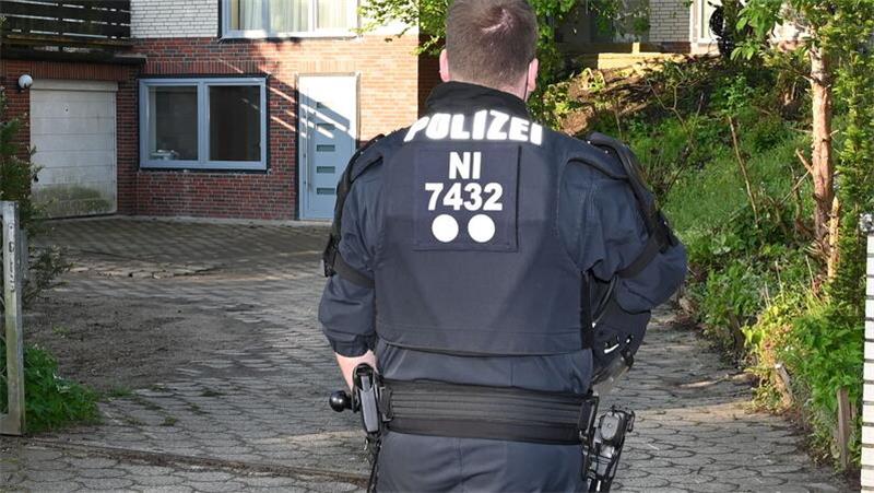 Tödliche Messerattacke in Stade: Polizei nimmt Verdächtigen nach Razzia fest Ein Polizeibeamter steht vor einem Objekt.