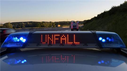 Ein Polizeifahrzeug warnt auf der Autobahn eine Leuchtschrift vor einer Unfallstelle.