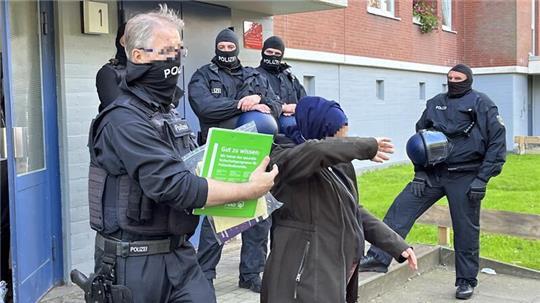 Ein Polizist führt ein mutmaßliches Mitglied der syrischen Schleuser-Bande nach der vorläufigen Festnahme in Stade ab.