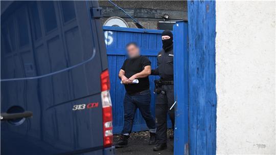 Ein Polizist führt einen Mann ab.
