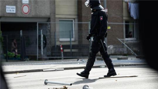 Ein Polizist geht an Metall- und Holzgegenständen vorbei, die vor einem unter Quarantäne gestellten Wohngebäude in der Göttinger Innenstadt auf dem Boden liegen.