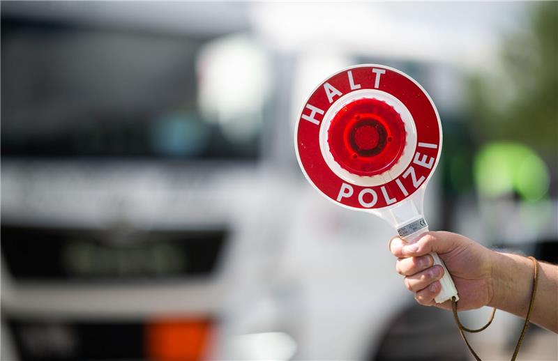 Alkoholisierter Autofahrer schläft auf A1-Standstreifen Ein Polizist hält bei einer Verkehrskontrolle eine Polizeikelle in der Hand.