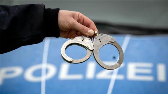 Ein Polizist hält ein Paar Handschellen.