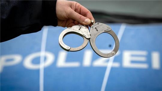 Ein Polizist hält ein Paar Handschellen.