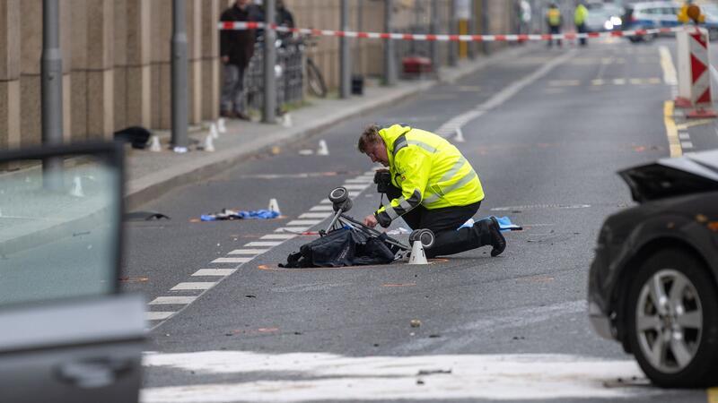 Ein Polizist kniet an der Unfallstelle neben dem zerstörten Kinderwagen.