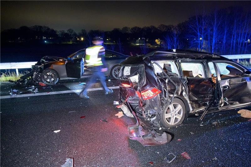 Ein Polizist läuft zwischen den stark beschädigten Unfallfahrzeugen auf der Autobahn. Foto: Jonas Walzberg/dpa