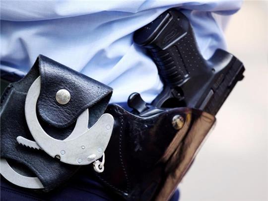 Ein Polizist mit Handschellen und Pistole am Gürtel. Foto: Oliver Berg/dpa/Symbolbild