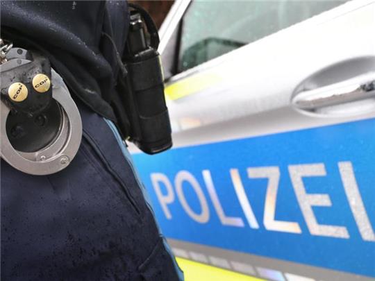 Ein Polizist mit Handschellen und einer Pistole am Gürtel steht vor einem Streifenwagen. Foto: Karl-Josef Hildenbrand/dpa