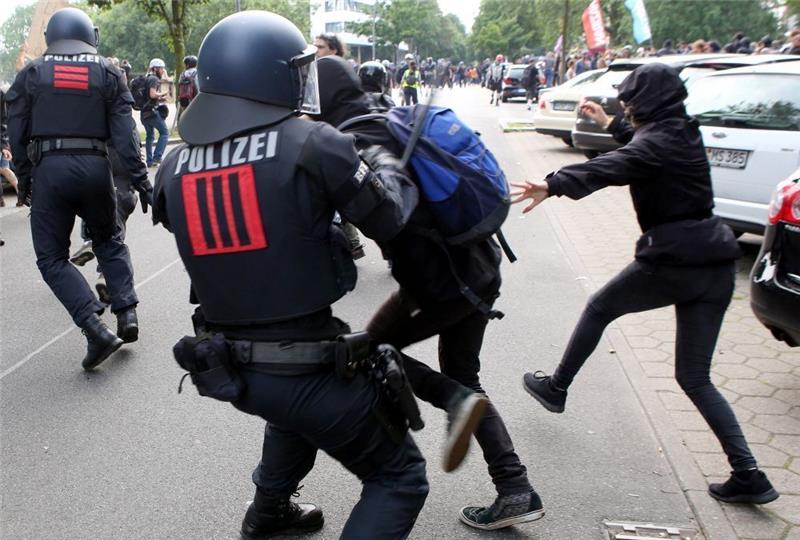 Ein Polizist setzt gegen Demonstranten nahe der Landungsbrücken in Hamburgs einen Schlagstock. Foto: Bodo Marks/dpa