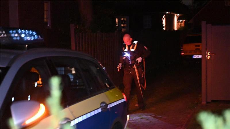 Ein Polizist sichert die Langwaffe, mit der die Kinder an der Haustür bedroht wurden.