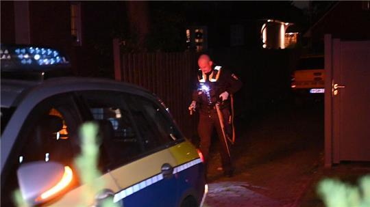 Ein Polizist sichert die Langwaffe, mit der die Kinder an der Haustür bedroht wurden.