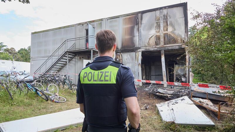 Ein Polizist steht vor der Brandruine der Flüchtlingsunterkunft in Buchholz.