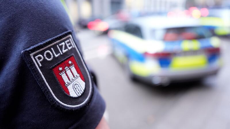 Polizei Hamburg macht Abstriche bei Auswahlkriterien für Bewerber Ein Polizist steht vor einem Einsatzfahrzeug der Polizei.