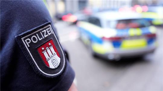 Ein Polizist steht vor einem Einsatzfahrzeug der Polizei.