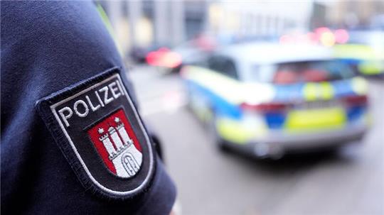 Ein Polizist steht vor einem Einsatzfahrzeug der Polizei.