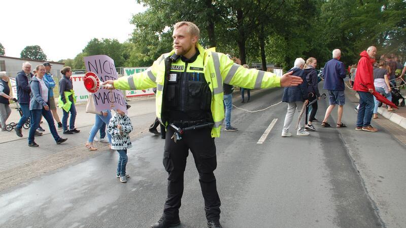 Ein Polizist stoppt den Autoverkehr, damit die Demonstranten als Menschenkette über die gefährliche Schwingestraße marschieren können.