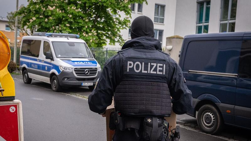 Ein Polizist trägt bei einem Einsatz in Bonn einen Karton mit beschlagnahmtem Material aus einem Gebäude.